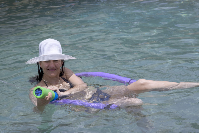 Woman with hat in swimming pool with watergun